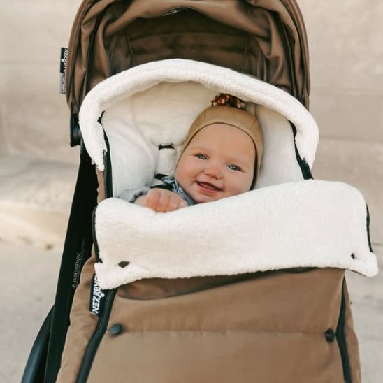 Bebe souriant dans son chanceliere poussette universelle beige