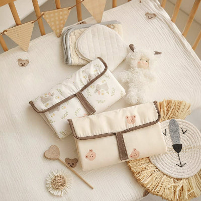 Tapis à langer nomade motifs ourson et lapins dans une lit de bébé