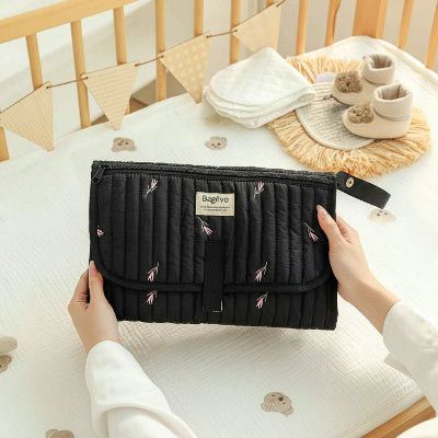 Tapis à langer nomade noir dans une pièce de chambre pour bébé