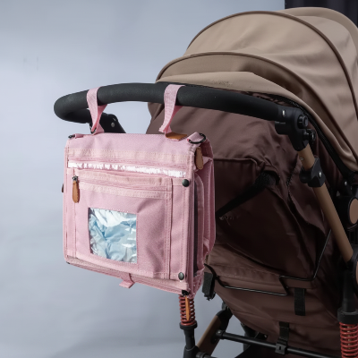 Tapis à langer nomade rose avec nombreuses poches de rangement pour bébé sur une poussette montrant l'Independence du produit 